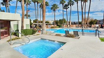 Springhill pool and hot tub view with tall trees around and lounging area near